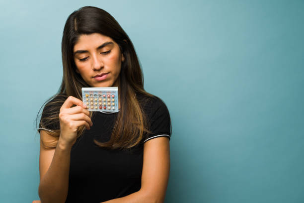 Hispanic woman taking hormone pills Gynecology concept. Healthy woman holding a blister of contraceptive pills. Young woman taking birth control pills contraceptive stock pictures, royalty-free photos & images