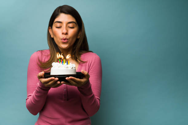 Celebrating a fun birthday Blowing the birthday candles. Attractive young woman making a wish while holding a delicious cake next to copy space woman birthday cake stock pictures, royalty-free photos & images
