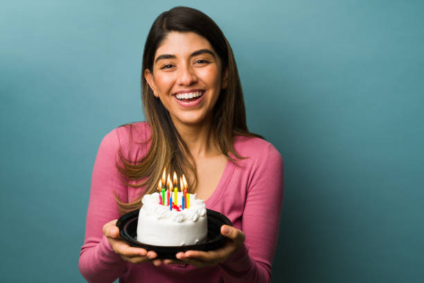 Happy birthday to me. Excited gorgeous woman holding a delicious cake and smiling while celebrating her birthday party