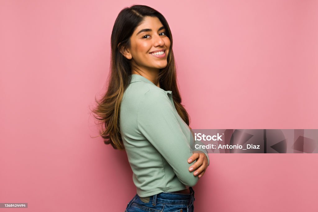 Studio portrait of a cheerful woman Side view of an attractive hispanic woman feeling happy in front of a bright pink background Women Stock Photo