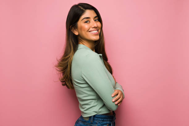 Studio portrait of a cheerful woman Side view of an attractive hispanic woman feeling happy in front of a bright pink background happiness photos stock pictures, royalty-free photos & images