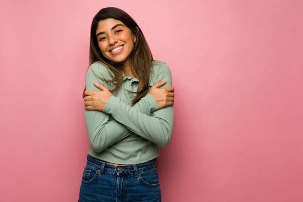 Loving woman embracing herself Self-love. Attractive young woman smiling while hugging herself and feeling grateful hugging self stock pictures, royalty-free photos & images