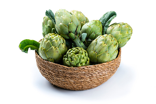 Close up view of fresh organic artichokes in a basket isolated white. High resolution 42Mp studio digital capture taken with SONY A7rII and Zeiss Batis 40mm F2.0 CF lens