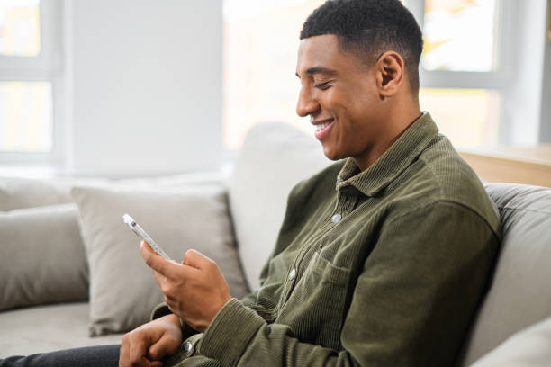 istock Portrait of smiling man sitting on sofa in office, using mobile phone for checking social nets, typing message for family, girlfriend, business partner 1368426507