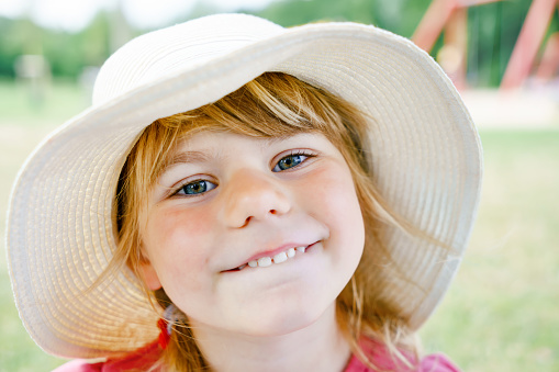 Portrait of redhead girl with freckles on summer blurred background. Cheerful and happy childhood