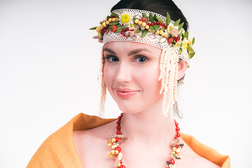 Close-up portrait of beautiful Russian woman wearing national accessories decorated with flowers and berries.