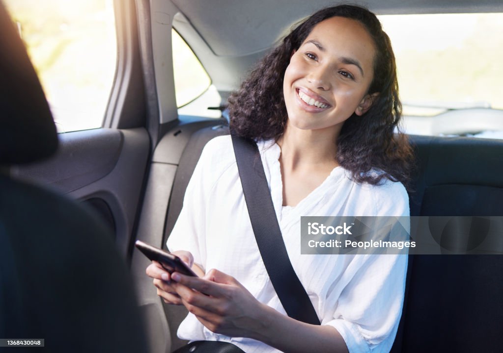 Cropped shot of an attractive young businesswoman sending a text while sitting in the backseat of a taxi Getting from one place to the next has never been easier Crowdsourced Taxi Stock Photo