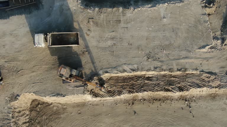 A truck unloads soil with huge boulders into a dump truck. Additional difficulties when performing earthwork