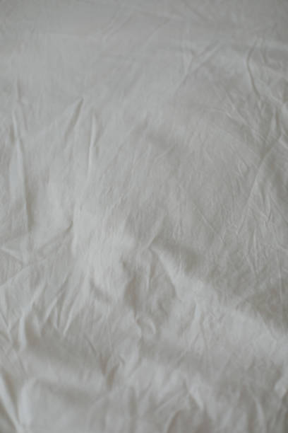 istock Fabric texture background. Wrinkled, crumpled fabric. Top view of a messy bedding sheet after night sleep. Unmade bed sheet in the bedroom after night sleep. Closeup textile background. Soft focus 1368432461
