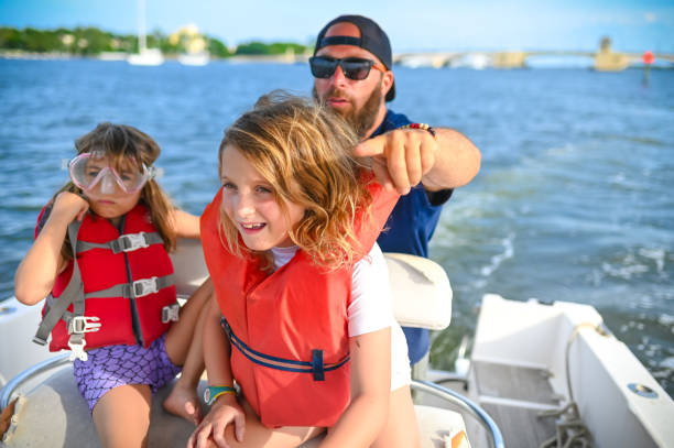 Family boat day, father and young daughters in life jackets on a speed boat enjoying a day on the water Family boat day family motorboat stock pictures, royalty-free photos & images