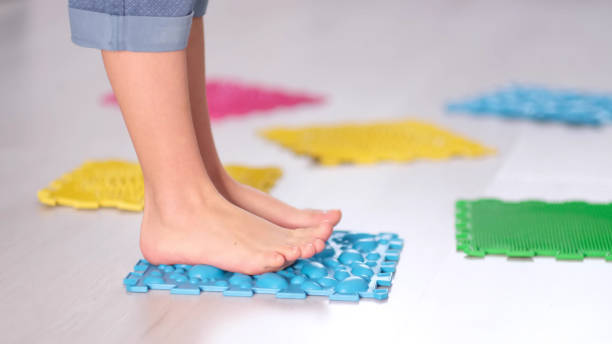 istock Little boy steps on orthopedic massage mats with different stiffness and texture. Feet Massage Using Trigger Point Spiky Massage Ball. Myofascial Release. close up 1368432689