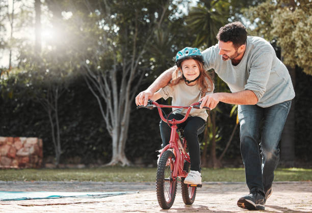istock Shot of a man assisting his daughter while riding a bicycle 1368432745