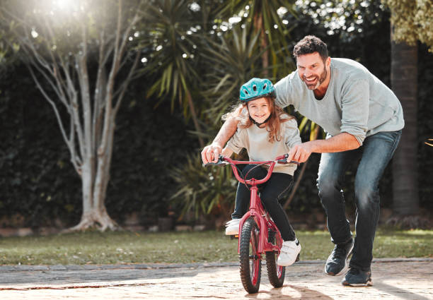 Shot of a man assisting his daughter while riding a bicycle