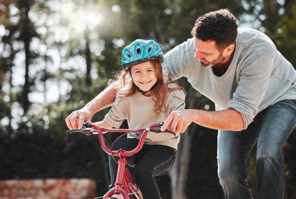 istock Shot of a man assisting his daughter while riding a bicycle 1368432749