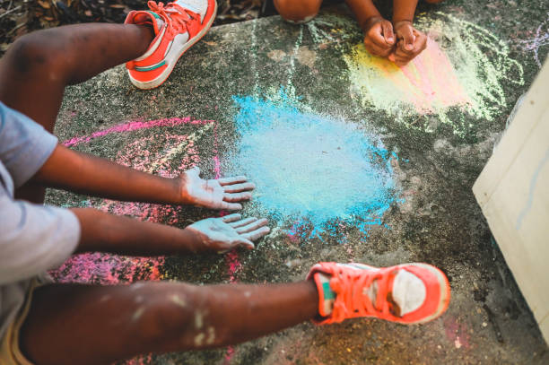 età elementare gruppo di razza mista di bambino che gioca con il gesso del marciapiede all'aperto - little girls sidewalk child chalk foto e immagini stock