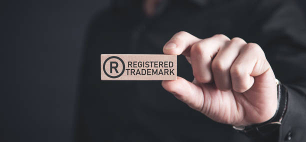 Male hand showing R-Registered trademark on wooden block. stock photo