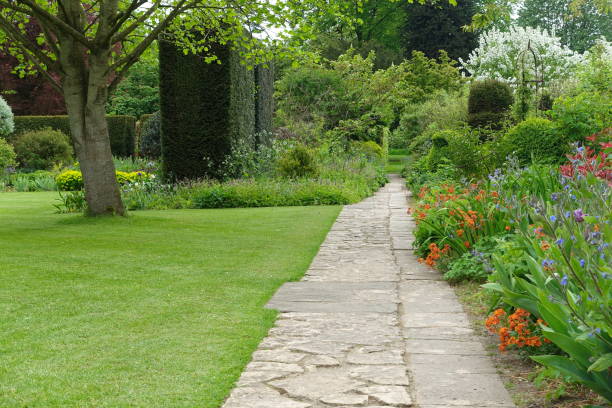 Garden Path Stone paved garden path with a grass lawn and beautiful flowers in bloom landscape design stock pictures, royalty-free photos & images