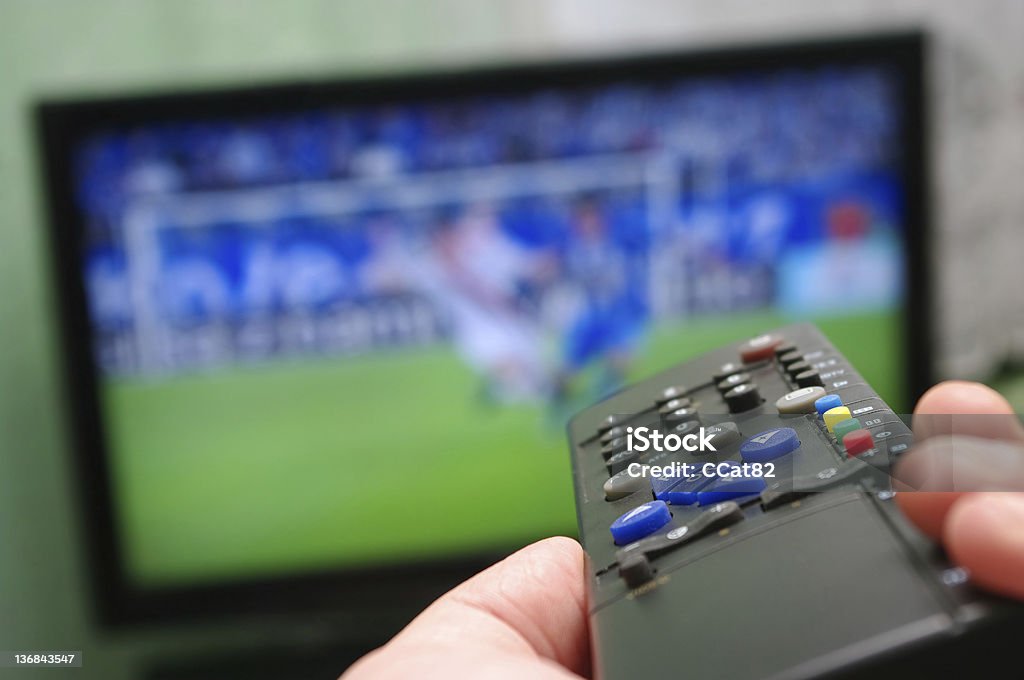 Football match and remote control Television Industry Stock Photo