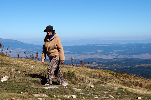 smiling elderly woman climb the mountain on a sunny day.