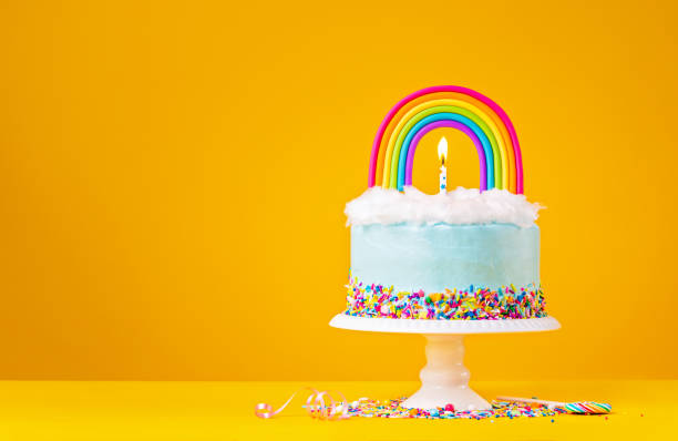 istock Blue Birthday Cake with Rainbow topper on Yellow Background 1368439216