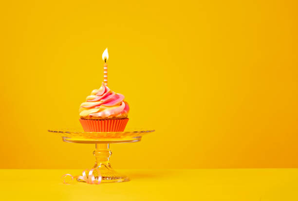 cupcake di compleanno con candela su giallo - ribbon nobody cupcake celebration foto e immagini stock