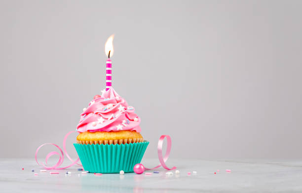 Pink Birthday Cupcake with Candle Cute pink Birthday cupcake with a candle and sprinkles over light grey background. Make a wish! birthday cake green stock pictures, royalty-free photos & images