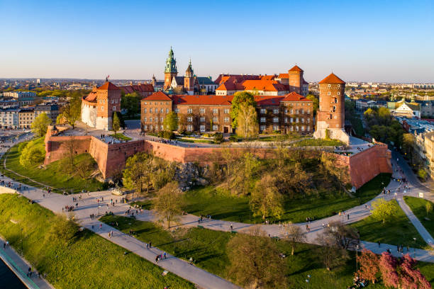 Krakow skyline, Poland, with Wawel Hill, Cathedral and castle Kraków, Poland – April 04, 2019:  Skyline panorama of Cracow old city with Wawel Hill,  Cathedral, Royal Wawel Castle, defensive walls, park, promenade and unrecognizable walking people. krakow stock pictures, royalty-free photos & images