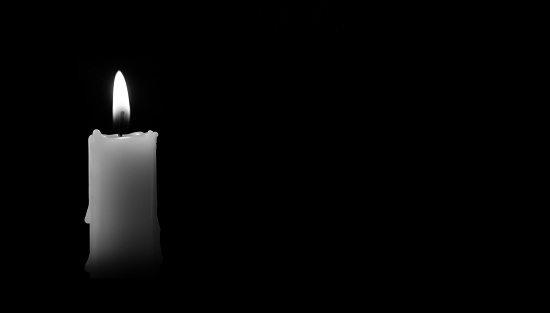 Candle burning in the black background. There's room for your text. Black and white photo. The concept of mourn, grief or mourning