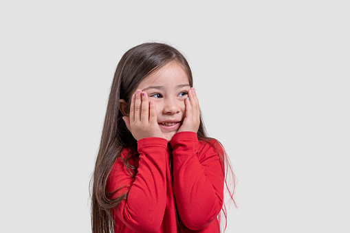 Portrait of a happy child girl with hands on her cheeks. Horizontal composition.