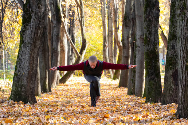 istock Sporty man practicing yoga in autumn park 1368450991
