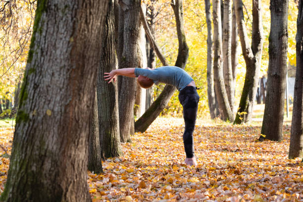 istock Sporty man practicing yoga in autumn park 1368452329