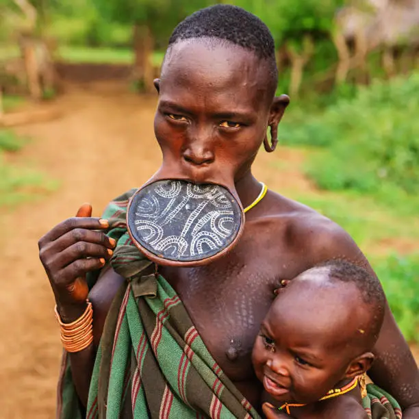 Woman from Mursi tribe breasfeeding her baby.  Mursi tribe are probably the last groups in Africa amongst whom it is still the norm for women to wear large pottery or wooden discs or ‘plates’ in their lower lips.