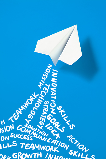 White paper plane on blue background with business related words