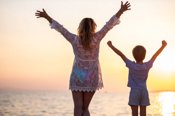 istock Rear view mother and son enjoying at the sunset on beach 1368454662