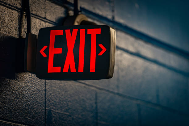 glowing exit sign by night on wall glowing exit sign by night on black wall exit sign photos stock pictures, royalty-free photos & images
