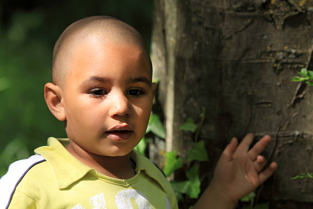 Little kid near a tree trunk