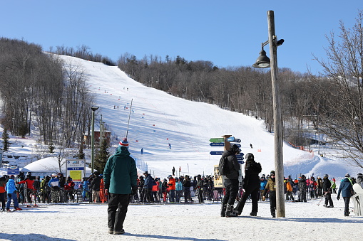 January 29, 2022 - The Blue Mountain, Ontario, Canada: View of the Blue Mountain and lots of people waiting in line for ski lift to get to the top of the mountain. Busy ski resort in Ontario, Canada. Skiing and snowboarding at the Blue Mountain in January 2022. Winter staycation in Ontario. Winter sports in Canada