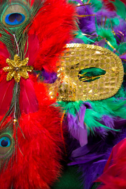 istock LV Mardi Gras sequined mask, decorated with feathers on a bed of feather Mardi Gras feather Boas. 1368457366