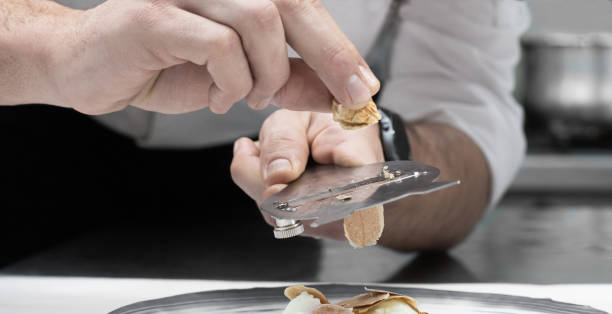 the chef cuts slices of white truffle in the kitchen selective focus stock photo