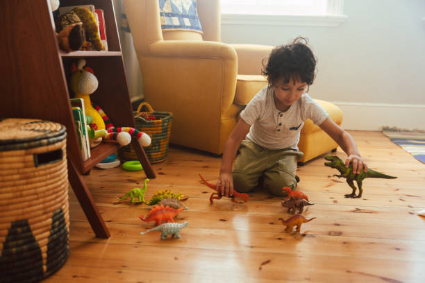 집에서 다채로운 공룡 장난감을 가지고 노는 어린 소년 - 동물 모양 뉴스 사진 이미지