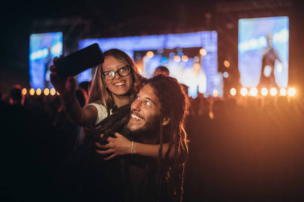 coppia che si fa un selfie con uno smartphone in un festival musicale - romantic scene foto e immagini stock