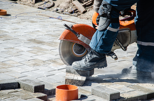 A worker cuts paving slabs with a gas cutter