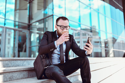 Businessman Arriving Early At Work And Drinking Coffee To Go Outside On Stairs