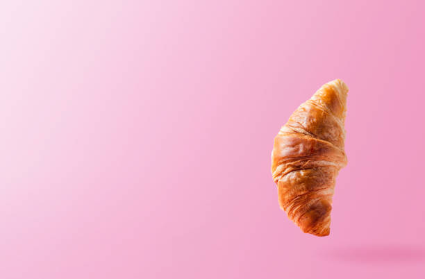 istock Croissant levitating or flying on pink background. Levitation, fly scene 1368467241