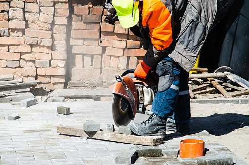 A worker cuts paving slabs with a gas cutter