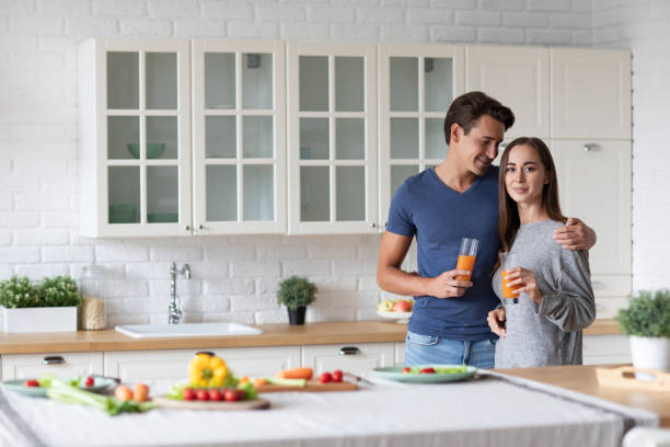 istock Happy couple in the kitchen with juice hugging, 1368469025