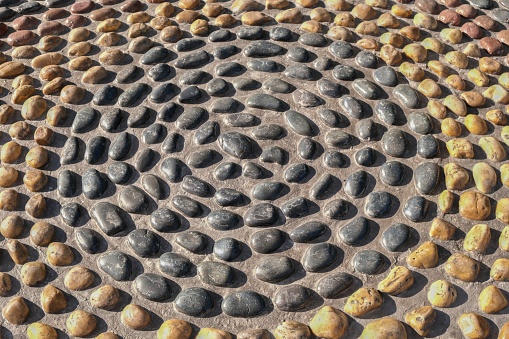 Mosaic circle pattern from convex rounded pebble stones. Ground path textured surface from boulders. Reflexology stone circle is design of cobblestones arranged in circle.