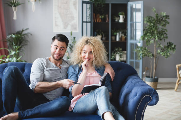 istock Young married couple with a notebook are counting finances on payments, time at home. 1368470035