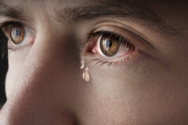 closeup of young crying man eyes with a tears - huilen stockfoto's en -beelden
