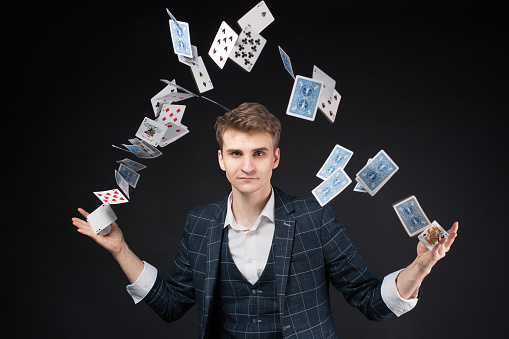A man throws a deck of playing cards in the air. Game over. Black background.